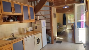 A kitchen with wooden cabinets, a washing machine, a sink, and a toaster.