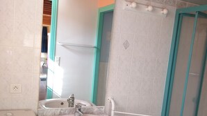 A bathroom with a white sink, a mirror, and a shower enclosure.
