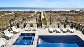 A pool area with lounge chairs and a view of the beach.