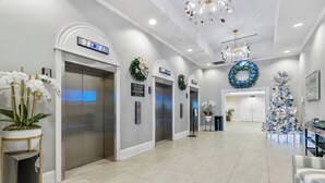 Un moderno vestíbulo de hotel con tres ascensores, un árbol de Navidad y una recepción.