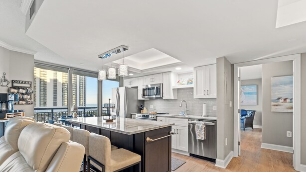 Una cocina moderna con una isla central, electrodomésticos de acero inoxidable y vistas a la ciudad.