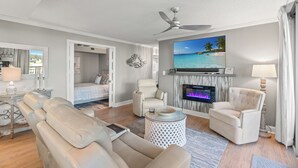 Una sala de estar moderna con un sofá, sillones, un televisor y una chimenea.