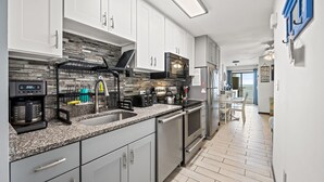 A modern kitchen with granite countertops, stainless steel appliances, and white cabinetry. - San A Bel 404 - Oceanfront Condo - Indoor Pool (North Myrtle Beach)