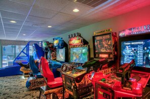 Une rangée de bornes d’arcade dans une pièce dont le sol est recouvert d’une moquette et qui possède un mur en verre.