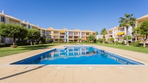 Un hotel con piscina central, varios balcones y abundante vegetación.