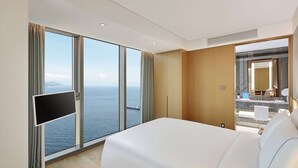 A modern hotel room with a large bed, a flat-screen TV, and a view of the sea. - Wyndham Grand Busan Ijin (Busan)