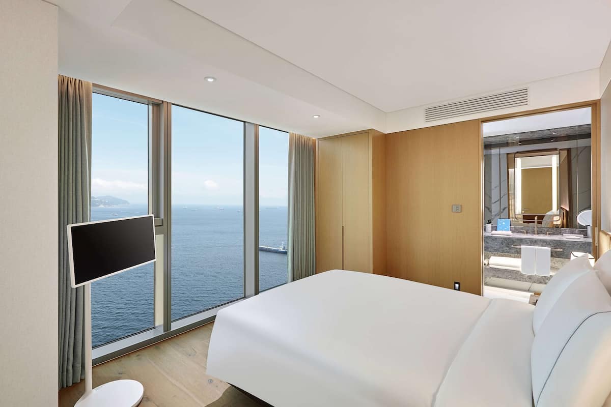 Ein modernes Hotelzimmer mit einem großen Bett, einem Flachbildfernseher und Blick auf das Meer.