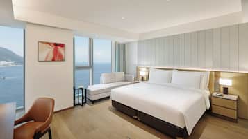 Une chambre d’hôtel moderne dotée d’un grand lit, d’un canapé, d’un bureau et offrant une vue sur la mer.