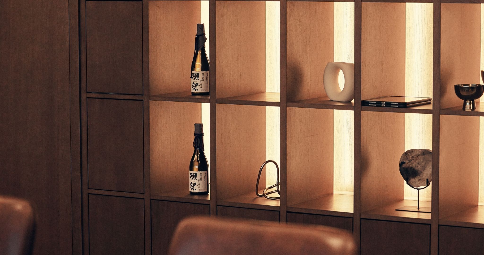 A wooden shelving unit with various items including bottles and a bowl.