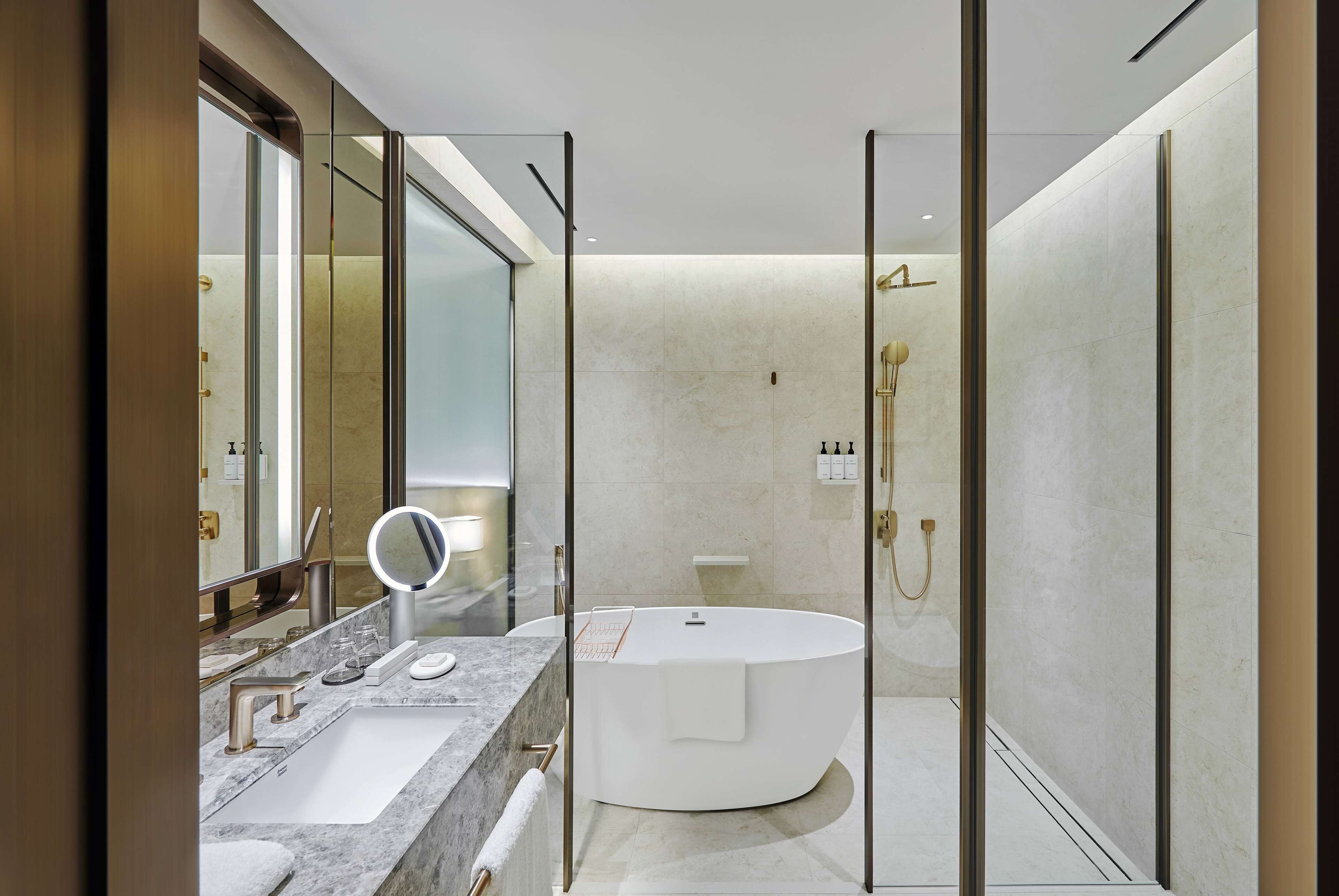 A modern bathroom with a large mirror, a round bathtub, and a glass-enclosed shower area.