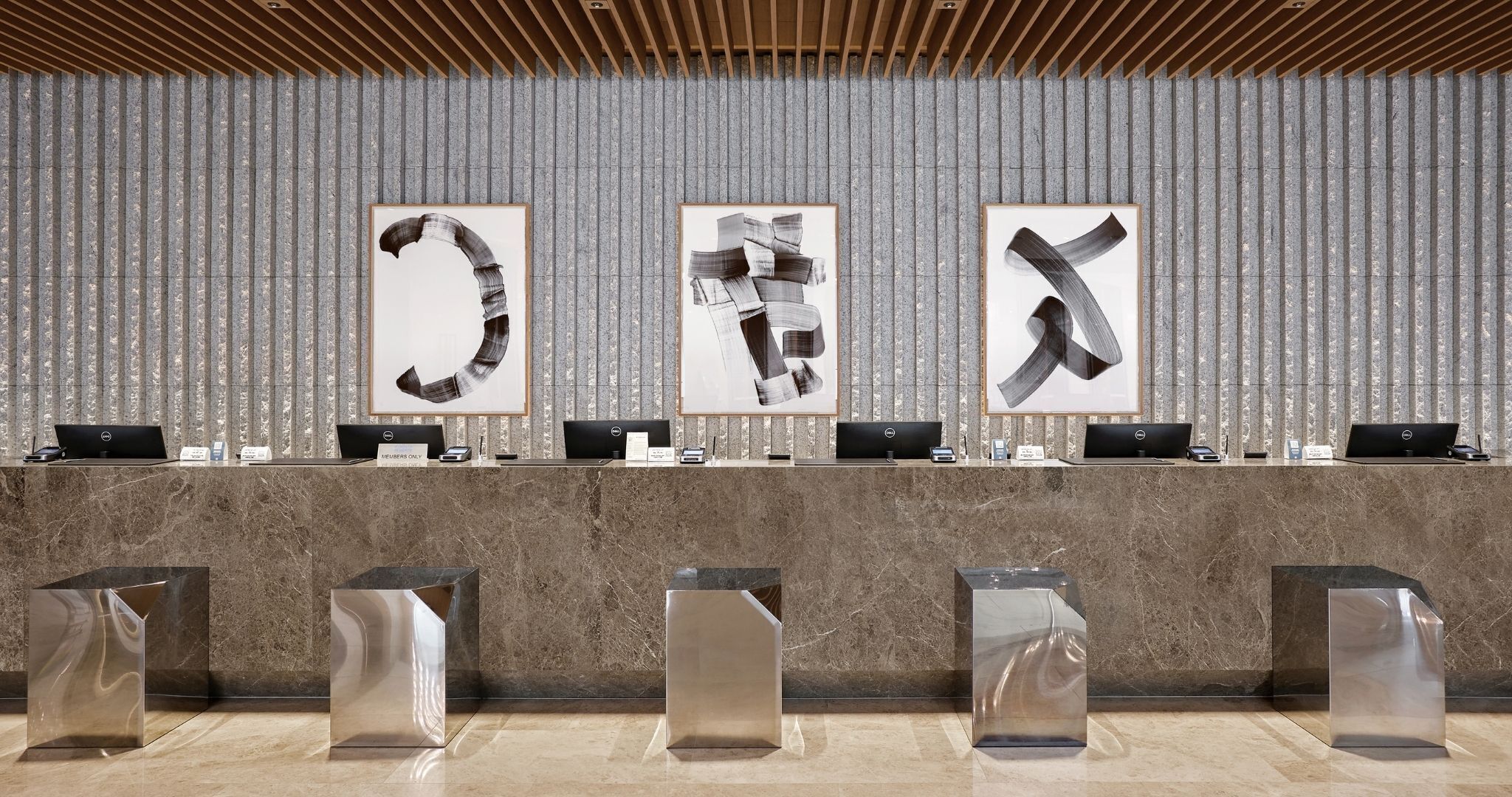 A reception desk with multiple laptops, framed abstract art, and modern chairs.