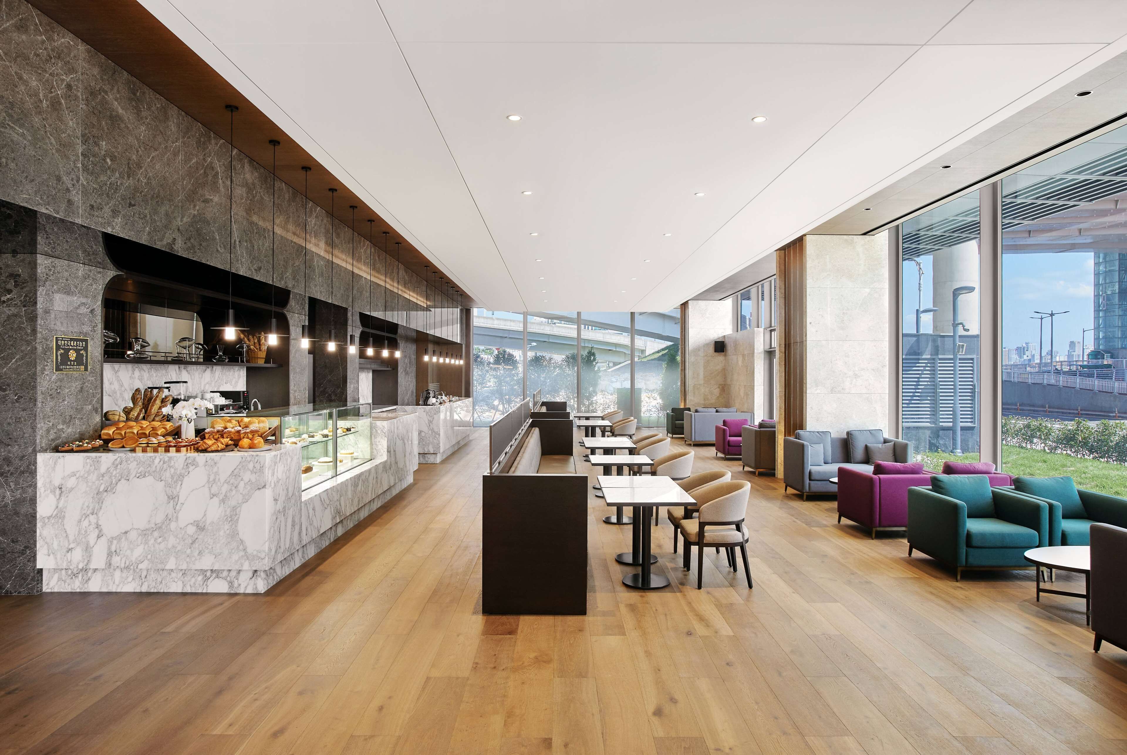A modern interior with marble counters, wooden flooring, and a seating area with colorful chairs.