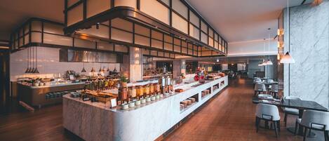 A modern restaurant with a central bar area, wooden flooring, and marble walls.