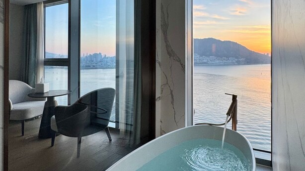 A modern room with a large bathtub, a chair, and a table. - Wyndham Grand Busan Ijin (Busan)