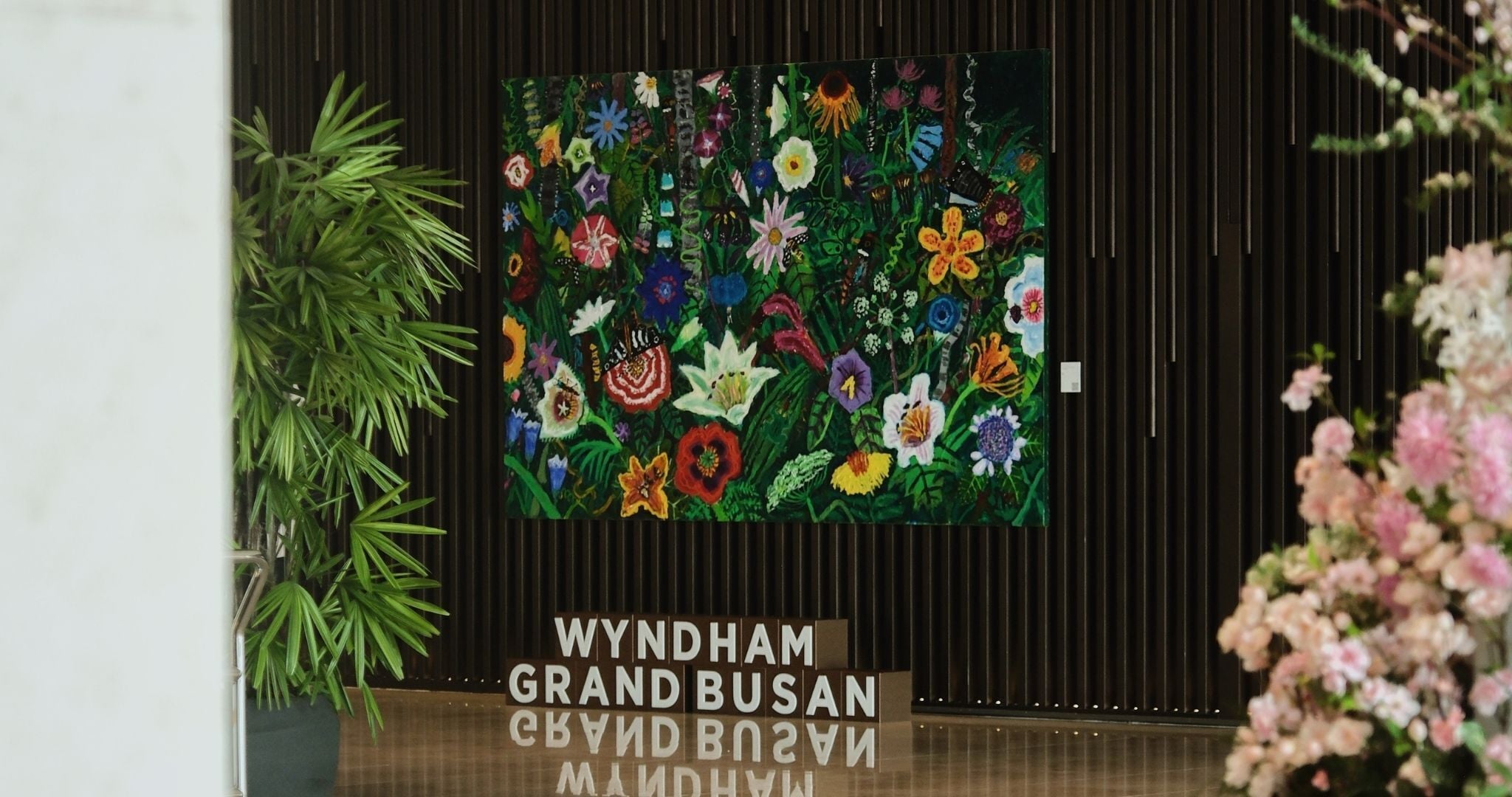 A framed floral artwork on a wall with the text "WYNDHAM GRAND BUSAN" below it.