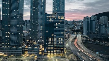 Un edificio de gran altura con varios pisos, rodeado de otros edificios altos, y una autopista concurrida llena de vehículos.