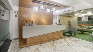 A reception desk with a wooden finish and a marble floor. - Treebo Urban, 1 Km From Railway Station (Surat)