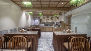 A dining area with wooden tables and chairs, a tiled backsplash, and hanging plants. - Treebo Urban, 1 Km From Railway Station (Surat)