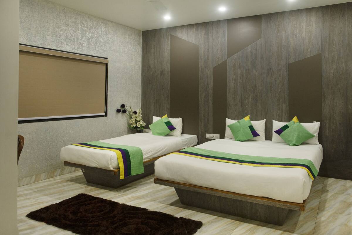 A hotel room with two beds, a large mirror, and a wooden floor.