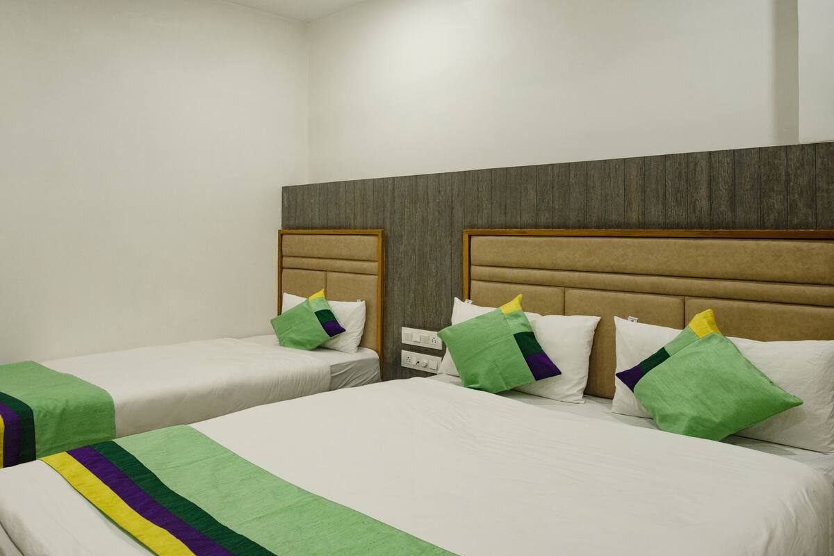 A hotel room with two beds, each with a headboard and pillows.
