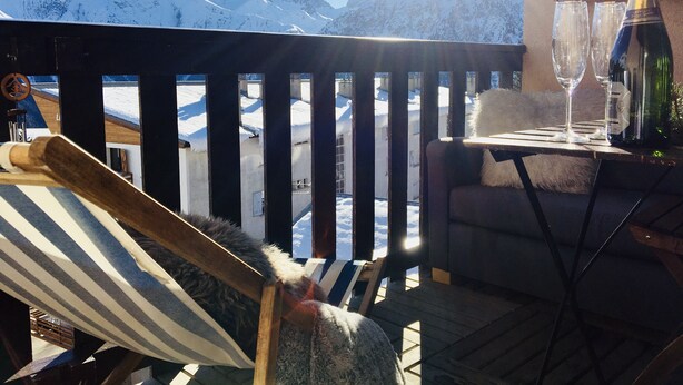 A deck with a view of snow-covered mountains, a bottle of champagne, and two glasses on a table. - Jolie Appartement Avec une Chemine,balcon Expose sud Avec Magnifique vue (Les Deux Alpes)
