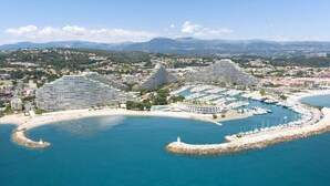 A coastal hotel with multiple buildings, a marina, and a beach. - Studio Port Marina Baie des Anges (Villeneuve-Loubet)