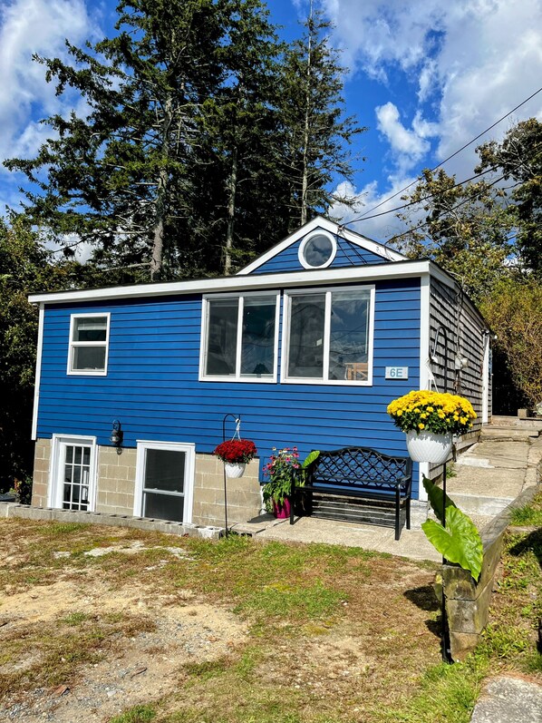 A two-story house with a blue exterior, a front porch, and a black bench. - Buttermilk Bay view, 2 bd room, beach & large deck (Bourne)