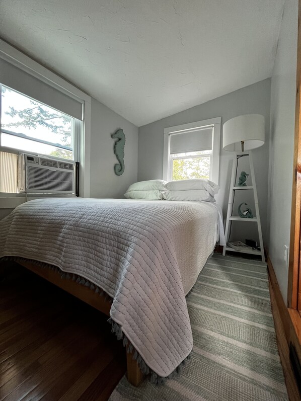 Une chambre à coucher avec un lit, une fenêtre, un radiateur, une lampe et une étagère.