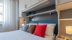 A hotel room with a bed, pillows, a nightstand, a lamp, and a shelf with a sign. - La Casa dei Viaggiatori by Wonderful Italy (Turin)