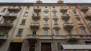 A multi-story building with balconies, a ground entrance, and a visible sign for a parking area. - La Casa dei Viaggiatori by Wonderful Italy (Turin)