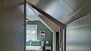 A bedroom with a bed, a nightstand, a lamp, and a window with blinds.