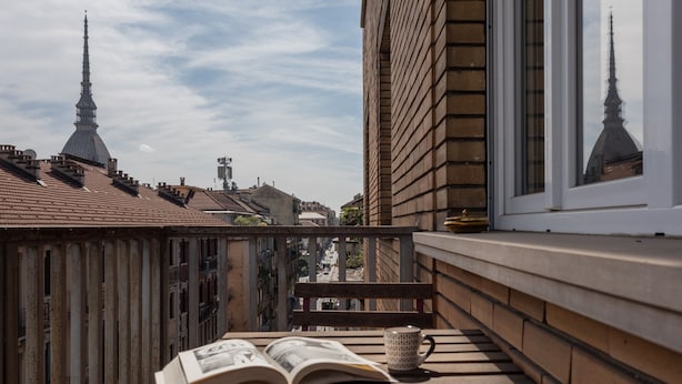 Un balcon avec une table en bois, un livre et une tasse.