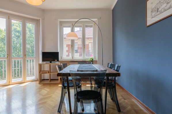 A dining area with a wooden table, chairs, and a television on a stand. - Mole View by Wonderful Italy (Turin)