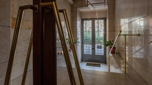 Un escalier en marbre avec une rampe en verre et une porte en haut.