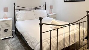A neatly made bed with white linens, a black metal headboard, and two bedside tables with lamps. - Stunning 2-bed Apartment in Maidstone (Maidstone)