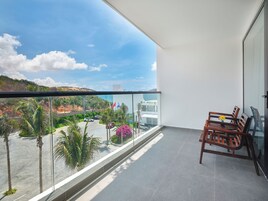 Un balcón con vistas a la costa, con palmeras y una carretera.