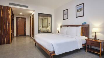 Habitación de hotel con una cama grande, cabecera de madera, dos mesitas de noche con lámparas, un espejo grande y un armario de madera.