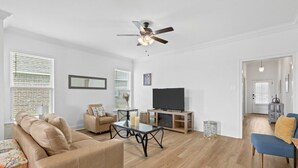Sala de estar com sofá, mesa de centro, TV e ventilador de teto.