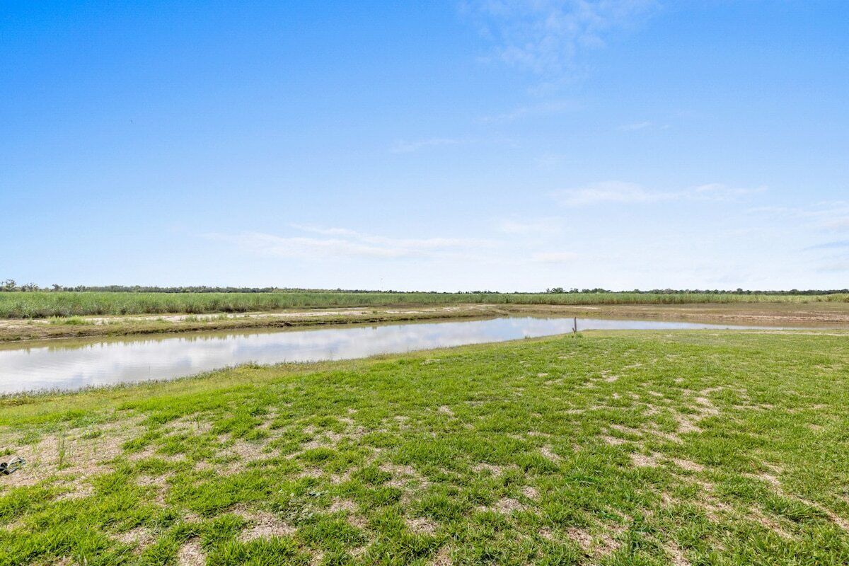 Paisaje plano con una masa de agua y campos verdes.