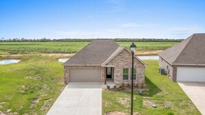 A residential property with a garage, a paved driveway, and a small front yard with a lamp post.