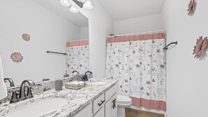A bathroom with two sinks, a mirror, and a shower curtain with floral and butterfly patterns.