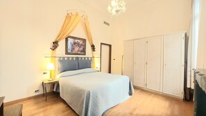 Ein Schlafzimmer mit einem Bett, zwei Nachttischlampen, einer Kristallleuchtre, einem Kleiderschrank und einem Bild an der Wand.