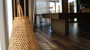 A room with a wooden floor, a woven basket hanging from the ceiling, and a bar area with stools. - Duas Quintas-areal T1 Varanda (Nespereira GMR)