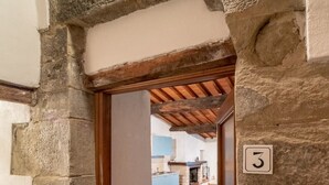 Ein von Steinmauern gesäumter Gang, der zu einem Raum mit der Nummer 3 führt, mit Holzboden und einem im Hintergrund erkennbaren Küchenbereich.