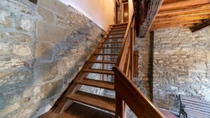 Una escalera de madera con paredes de piedra que conduce a un nivel superior.