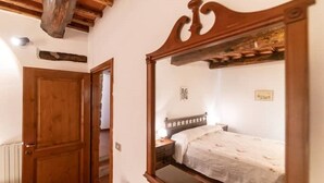 Een slaapkamer met een houten bedframe, nachtkastje en spiegel.
