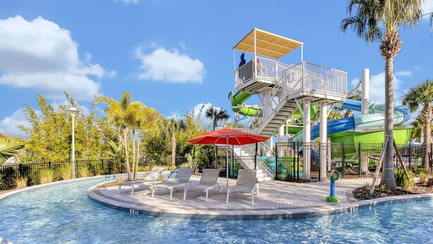 A pool area with a water slide, lounge chairs, and a lifeguard tower. - Luxury Retreat: Windsor Island Villa with Private Pool and Game Room (Davenport)