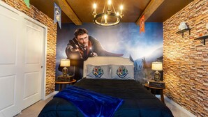 A bedroom with a stone wall, a large poster of a wizard, a chandelier, and two bedside lamps. - Luxury Retreat: Windsor Island Villa with Private Pool and Game Room (Davenport)
