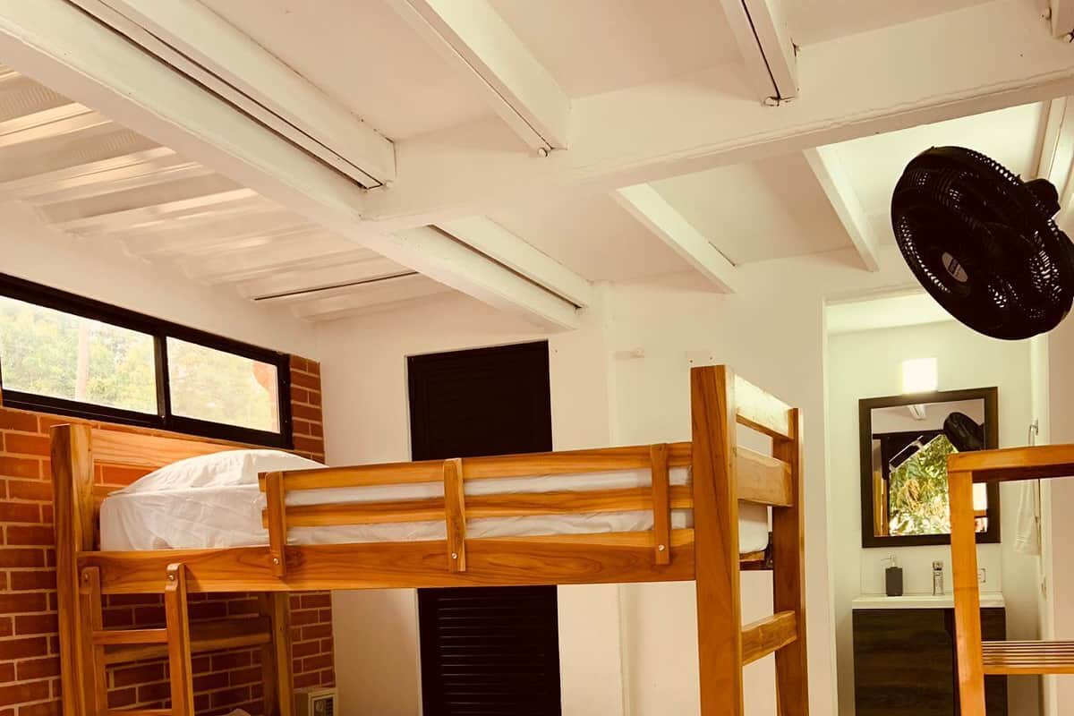 Dormitorio con literas, pared de ladrillo, ventana y espejo.