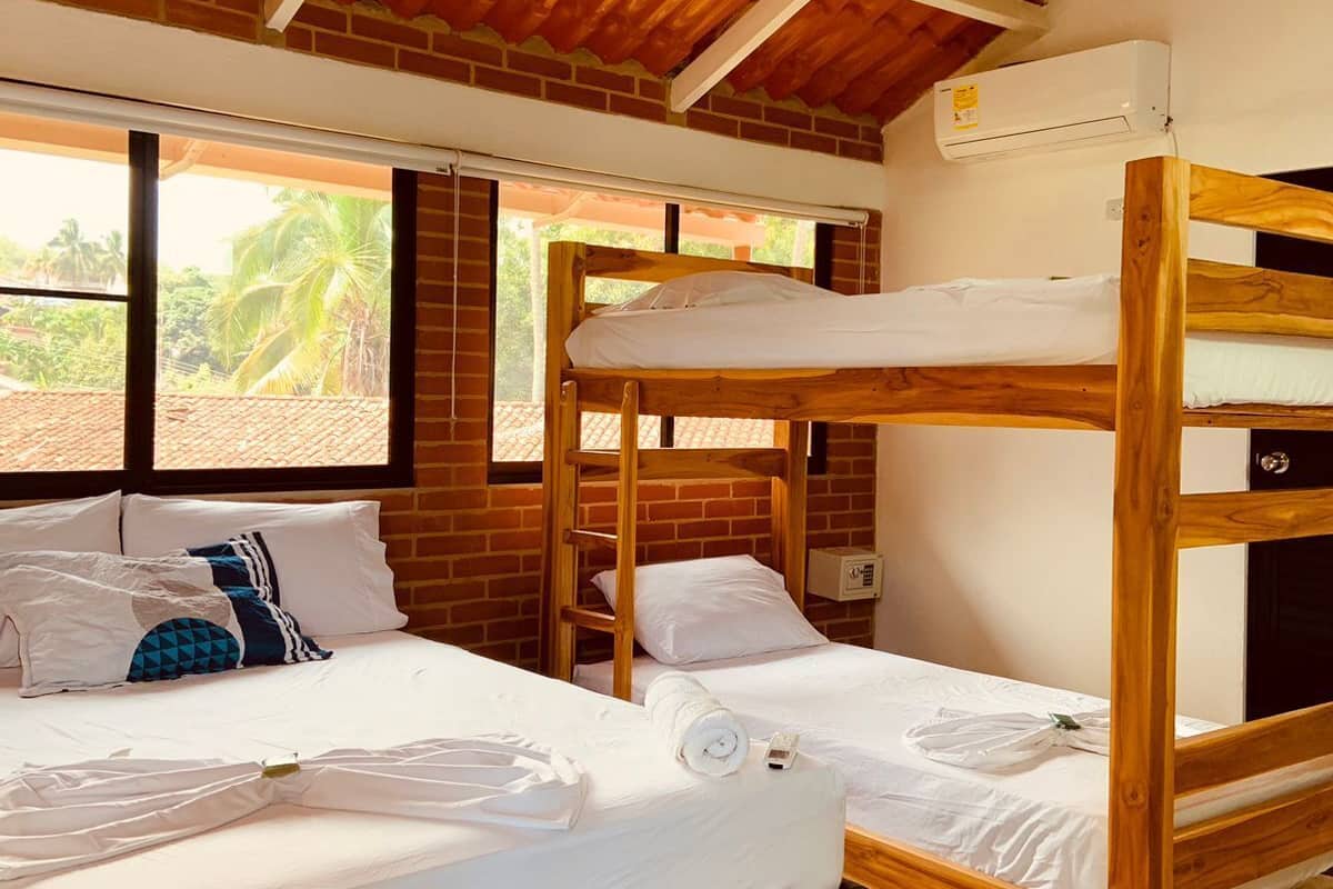 Un dormitorio con dos literas, una pared de ladrillo y una ventana con vista a palmeras.